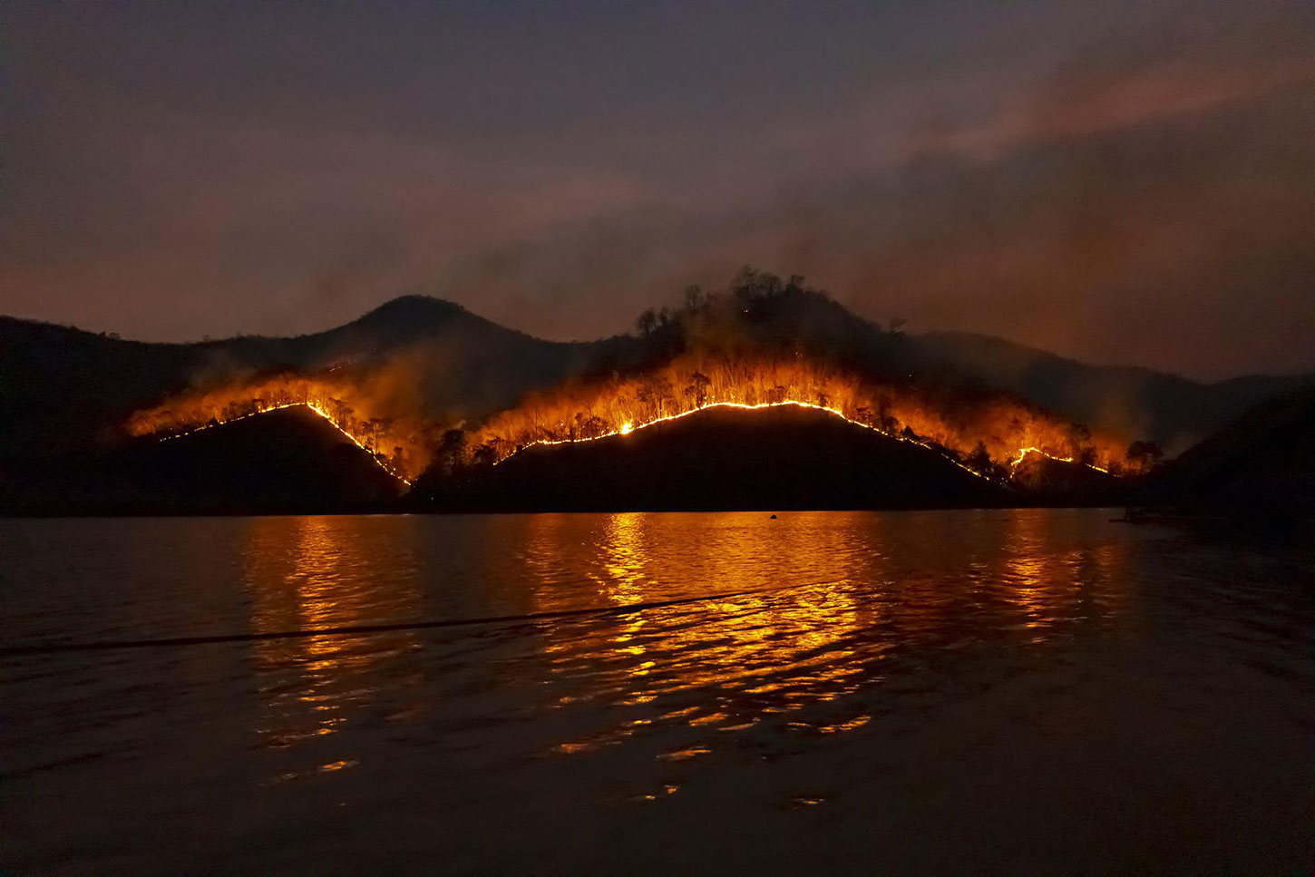 Wildfire on hills reflected in water